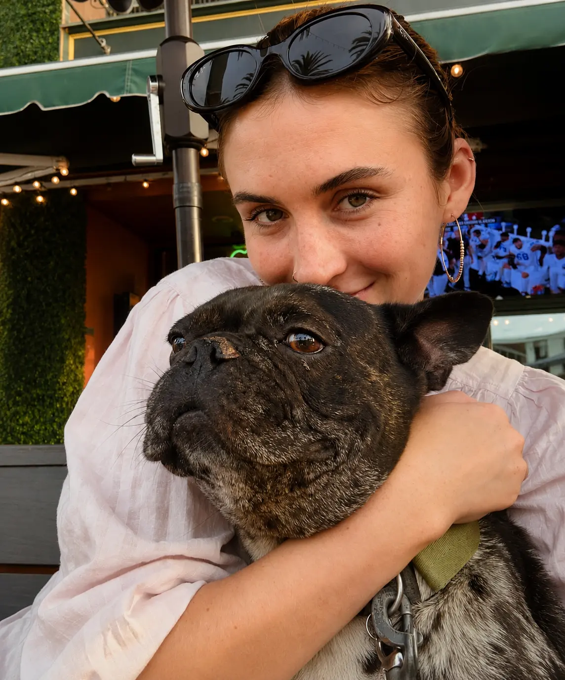 A guest hugging a brindle French bulldog under the green awning at Patrick Molloy's